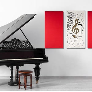 May include: A black grand piano with an open lid, a music stand with a lyre design, and three acoustic panels on the wall. The panels are red, white with a treble clef design, and red.