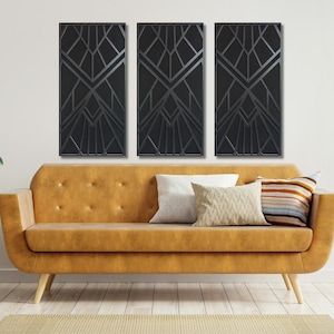 May include: Three black and white geometric art prints with a modern design hang above a brown leather sofa with throw pillows.