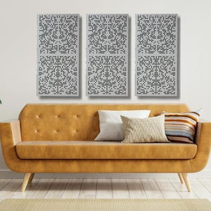 May include: A modern living room setup featuring a mustard-colored sofa with decorative pillows. Above the sofa, three rectangular wall panels with a geometric pattern are displayed. The room is decorated with plants and a small side table.