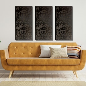 May include: Three black and gold abstract wall art panels with a geometric pattern. The panels are hanging on a white wall above a brown leather sofa with throw pillows.