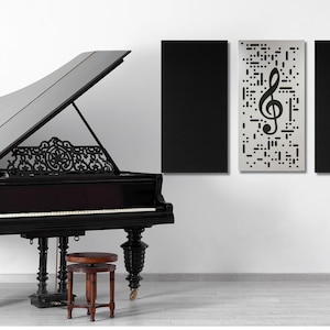 May include: A black grand piano with the lid open, a music stand with a lyre, and three black acoustic panels with a treble clef design on one panel. The panels are mounted on a white wall.