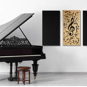 May include: A black grand piano with an open lid, a wooden music stand with a lyre, and three black acoustic panels on a white wall. The center panel features a gold background with a black treble clef cutout.