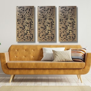 May include: Three rectangular wall panels with a geometric pattern of black squares and rectangles on a light brown background. The panels are hanging on a white wall above a brown leather sofa.