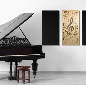 May include: A black grand piano with an open lid, a black and gold treble clef acoustic panel, and a black acoustic panel on a white wall. A gold metal music stand with a lyre design is in the corner.