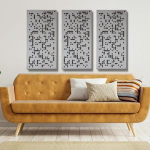 May include: Three gray rectangular wall panels with a black geometric pattern. The panels are hanging on a white wall above a brown couch with a patterned throw pillow.