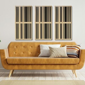 May include: Three rectangular wall panels with a black and white striped pattern. The panels are hanging on a white wall above a brown couch.