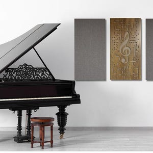 May include: A black grand piano with an open lid, a wooden music stand with a treble clef design, and three acoustic panels on the wall. Two of the panels are gray and one is brown with a treble clef design.