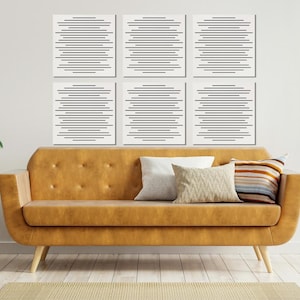 May include: A modern living room scene featuring a mustard-colored sofa with decorative pillows, a wooden side table, and six framed abstract art pieces with horizontal black lines. Plants in vases and pots add a touch of nature.