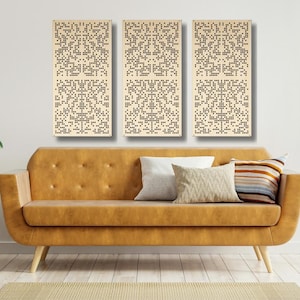 May include: Three beige wood panels with a geometric pattern of small black circles. The panels are hanging on a white wall above a brown leather couch with three pillows.