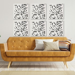 May include: Six black and white abstract geometric wall art prints arranged in a grid pattern above a brown couch with pillows. The couch is in a living room setting with a potted plant on a wooden stand to the right and a potted plant on a wooden side table to the left.