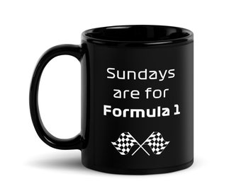 Puede incluir: Taza de café de cerámica negra con texto blanco que dice "Sundays are for Formula 1" y dos banderas a cuadros cruzadas.