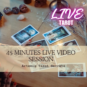 May include: A wooden table with tarot cards spread out on it. A hand is reaching for a card. The text "LIVE TAROT" is in pink letters on a white background. The text "45 MINUTES LIVE VIDEO SESSION" is in white letters on a beige background. The text "Artemis Tarot Secrets" is in white letters on a beige background.
