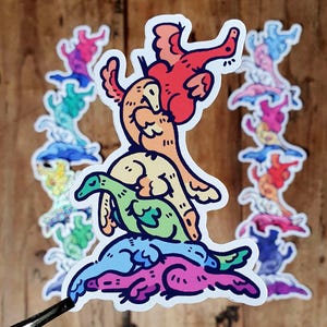 Può includere: Una pila di adesivi colorati con creature in stile cartone animato nei toni del rosso, arancione, giallo, verde, blu e viola. Gli adesivi sono disposti su una superficie di legno, con un paio di pinzette visibili in basso.