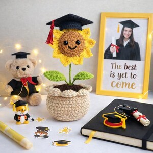 Puede incluir: Un girasol de ganchillo con birrete en una maceta beige. Tambi&eacute;n hay un oso de peluche con toga de graduaci&oacute;n y una foto enmarcada con el texto "The best is yet to come". Decoraci&oacute;n tem&aacute;tica de graduaci&oacute;n.