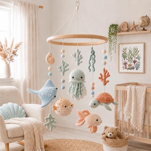 May include: A nursery mobile featuring crocheted sea creatures including a blue stingray, a light green jellyfish, a pufferfish, a sea turtle, and a goldfish, suspended from a wooden ring with coral and shell accents in soft pastel colors.