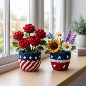 May include: Two crochet flower arrangements in patriotic-themed pots. One pot features red roses, the other a mix of sunflowers, daisies, and lavender. The pots are blue, red, and white, with star and stripe designs.