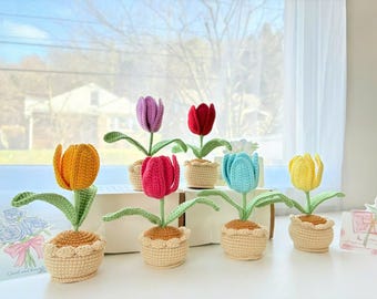 May include: Seven crocheted tulip flower arrangements in different colors, including yellow, orange, pink, red, purple, blue, and green. Each flower is in a crocheted pot.
