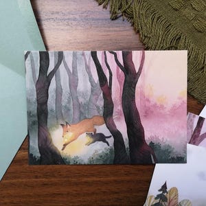 Può includere: Illustrazione ad acquerello di una volpe e un gatto che saltano attraverso una foresta. L'opera presenta una calda tavolozza di colori con una fonte di luce brillante, creando una scena stravagante. La foresta è raffigurata con alberi alti e scuri e uno sfondo rosato.