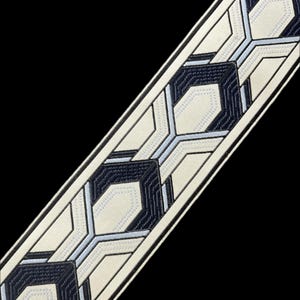 May include: White fabric trim with a geometric pattern in black and light blue. The pattern is made up of repeating hexagonal shapes.