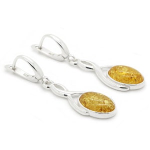 Peut inclure: Une paire de boucles d'oreilles pendantes en argent avec des pierres ovales en ambre. Les boucles d'oreilles ont un design torsadé et une fermeture à crochet.