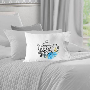 May include: White pillow with a black line drawing of a teapot with blue and yellow flowers.