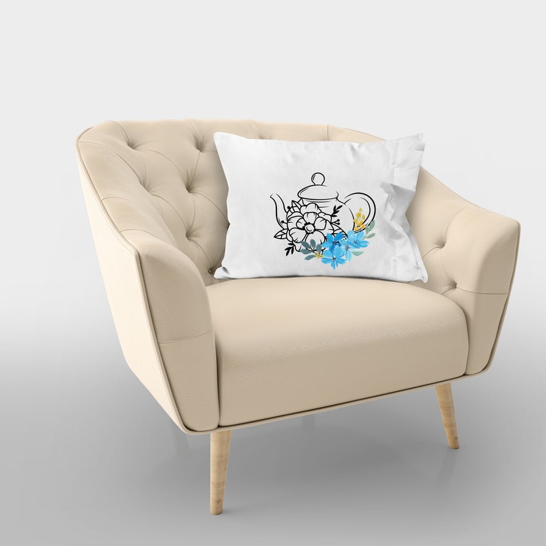 May include: A white throw pillow with a black line drawing of a teapot with blue and yellow flowers.