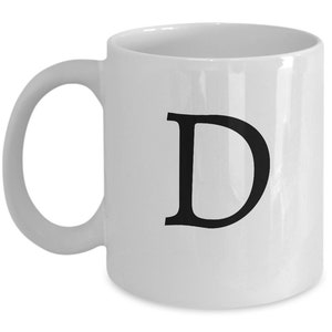 May include: White ceramic coffee mug with a black letter D printed on the front.