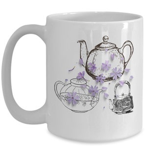 Puede incluir: Taza de cerámica blanca con una ilustración en blanco y negro de tres teteras y detalles de flores moradas. Las teteras son de diferentes estilos, una con un diseño ornamentado. La taza tiene un asa curva.