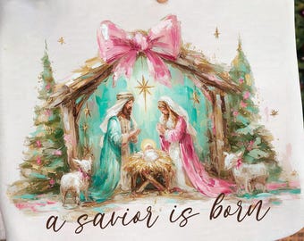 Peut inclure: Tissu blanc avec une peinture à l'aquarelle d'une scène de la Nativité. L'œuvre représente Marie, Joseph, l'enfant Jésus et deux agneaux. Le texte "a savior is born" est écrit en script. Un grand nœud rose est en haut.