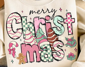 Può includere: Felpa color crema con la scritta "merry Christmas" in un font colorato e stravagante. Il design include alberi di Natale, un bastoncino di zucchero e un omino di pan di zenzero. La felpa è abbinata a jeans blu, un cappello e sandali.