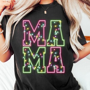 May include: Black t-shirt with the word "MAMA" in large, neon-style letters. The letters are outlined in green and pink, with colorful string lights inside. A casual, comfortable top.