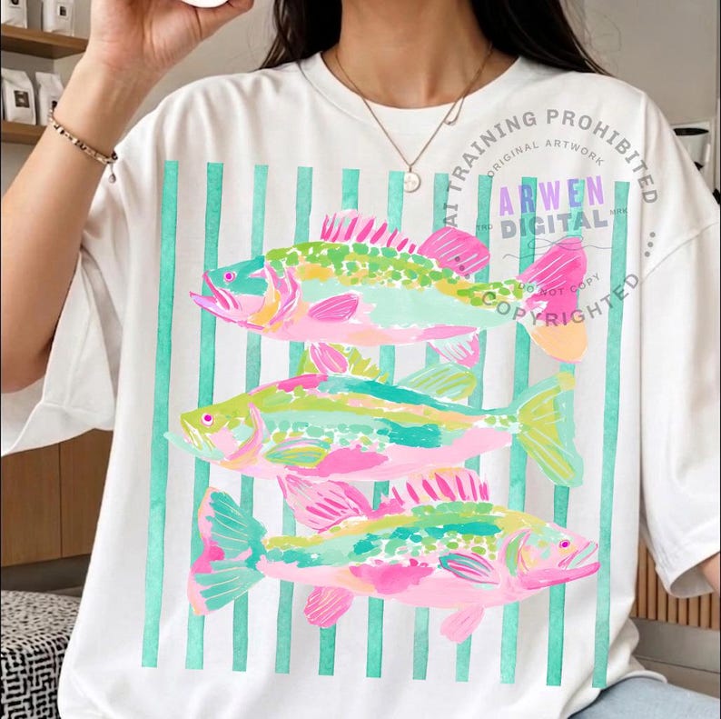 May include: White t-shirt featuring a colorful fish design. The design includes three fish in shades of pink, green, and yellow, set against a backdrop of vertical teal stripes. The text "ARWEN DIGITAL" is visible.