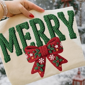 May include: A cream-colored pillow with the word "MERRY" in green, knitted-style letters. A red bow with white snowflakes, green holly leaves, and yellow stars is below the word. The pillow is held by a person with a bracelet and red nail polish.