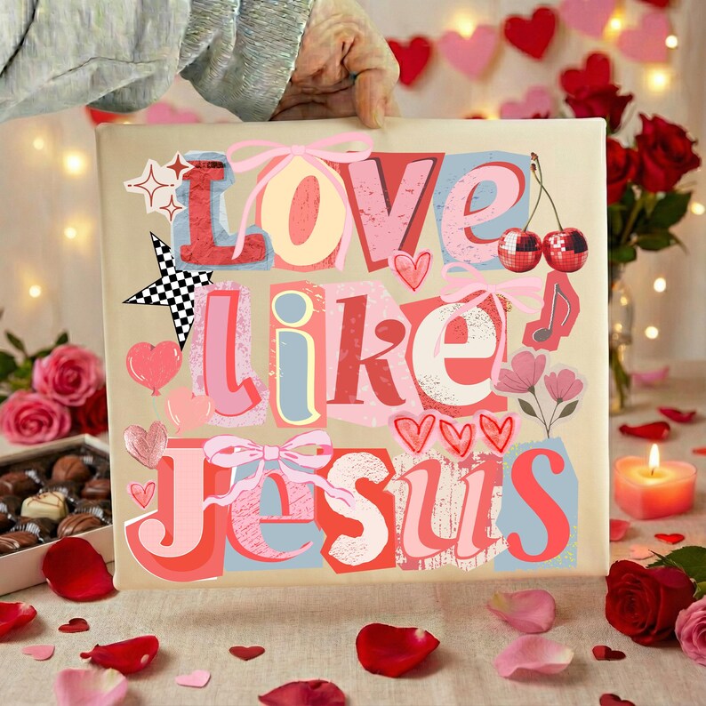 May include: A square canvas print with the words "Love Like Jesus" in a colourful, layered design. The artwork features hearts, bows, stars, and musical notes. The background is a neutral beige, with a hand holding the print.