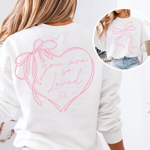 May include: White sweatshirt with a pink heart design and the text "you are so loved John 3:16".