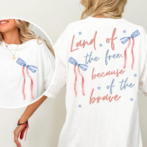 May include: White t-shirt with a red, white, and blue bow and the text "Land of the free, because of the brave" printed on the back.