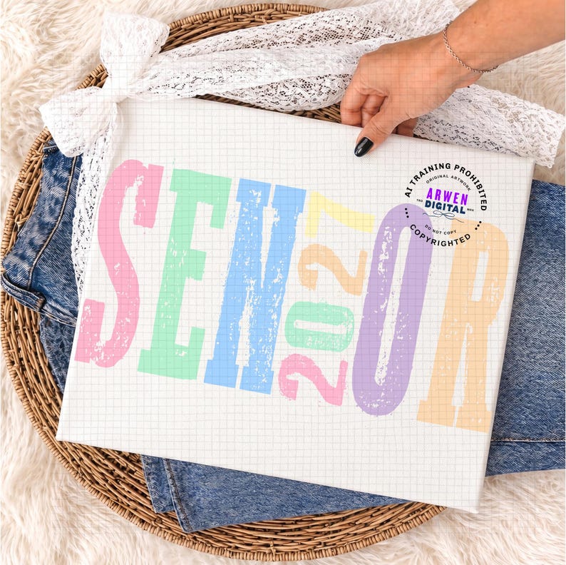 Puede incluir: Un lienzo rectangular blanco con un patr&oacute;n de cuadr&iacute;cula que presenta el texto colorido SENIOR 2027 en un estilo de letras de bloque desgastadas. Las letras son de color rosa, verde, azul, amarillo y morado. Un logotipo circular con el texto ARWEN DIGITAL es visible.