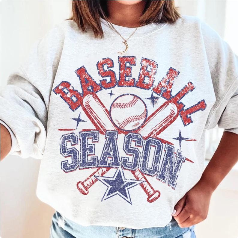 May include: A gray sweatshirt with a vintage-style graphic design featuring the text "Baseball Season" in red and blue lettering. The graphic also includes two crossed baseball bats and a baseball.