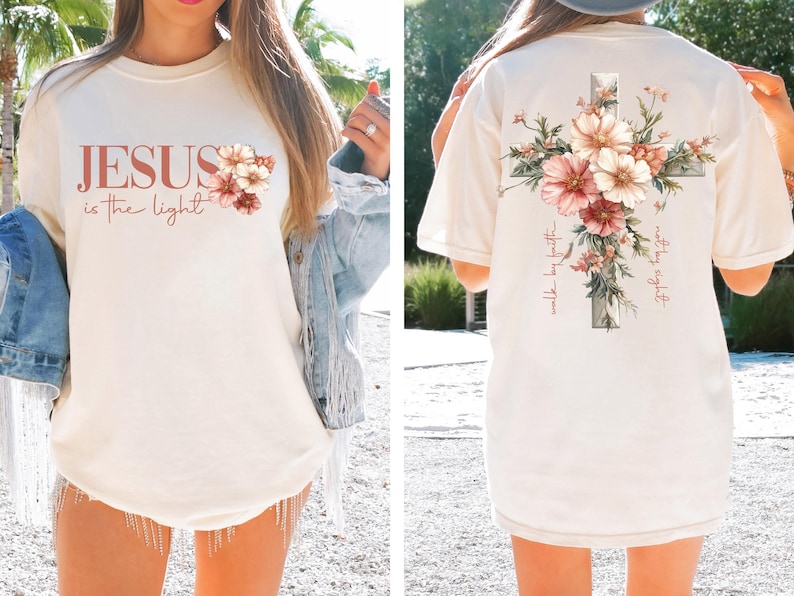 May include: A white t-shirt with a floral cross design on the back and the text "Jesus is the light" and a floral design on the front.