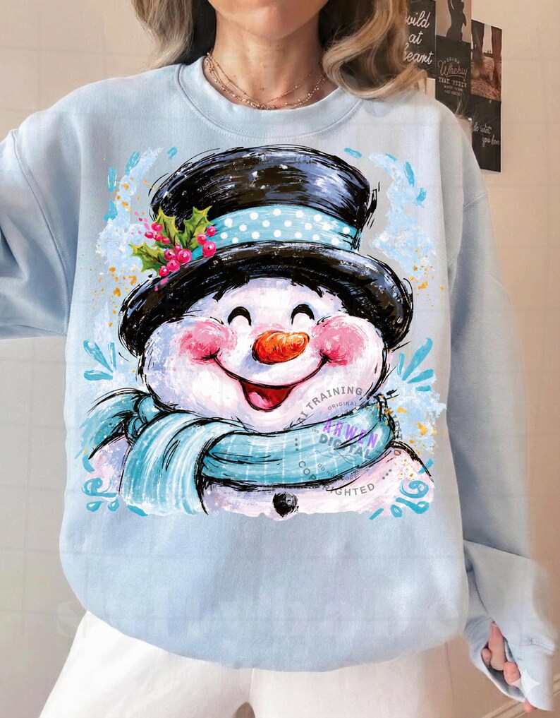 May include: A light blue sweatshirt featuring a graphic illustration of a smiling snowman wearing a black top hat with a light blue polka dot band, a light blue scarf, and a sprig of holly with red berries. The snowman has a carrot nose.