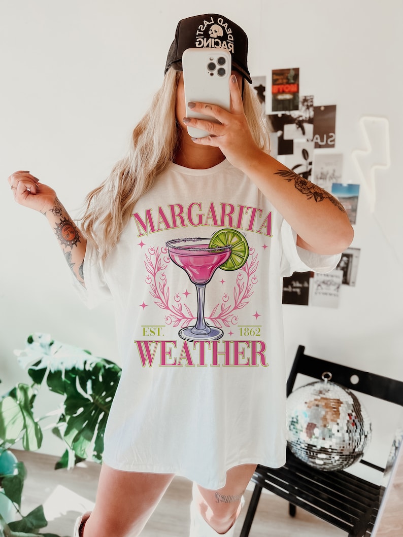 May include: White t-shirt featuring a pink margarita graphic and the text "Margarita Weather" with "Est. 1862" underneath.