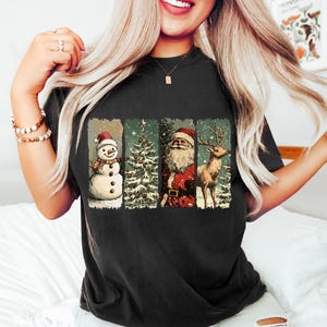 Może przedstawiać: Czarny T-shirt z vintage świątecznym wzorem przedstawiającym bałwana, choinkę, Świętego Mikołaja i renifera.