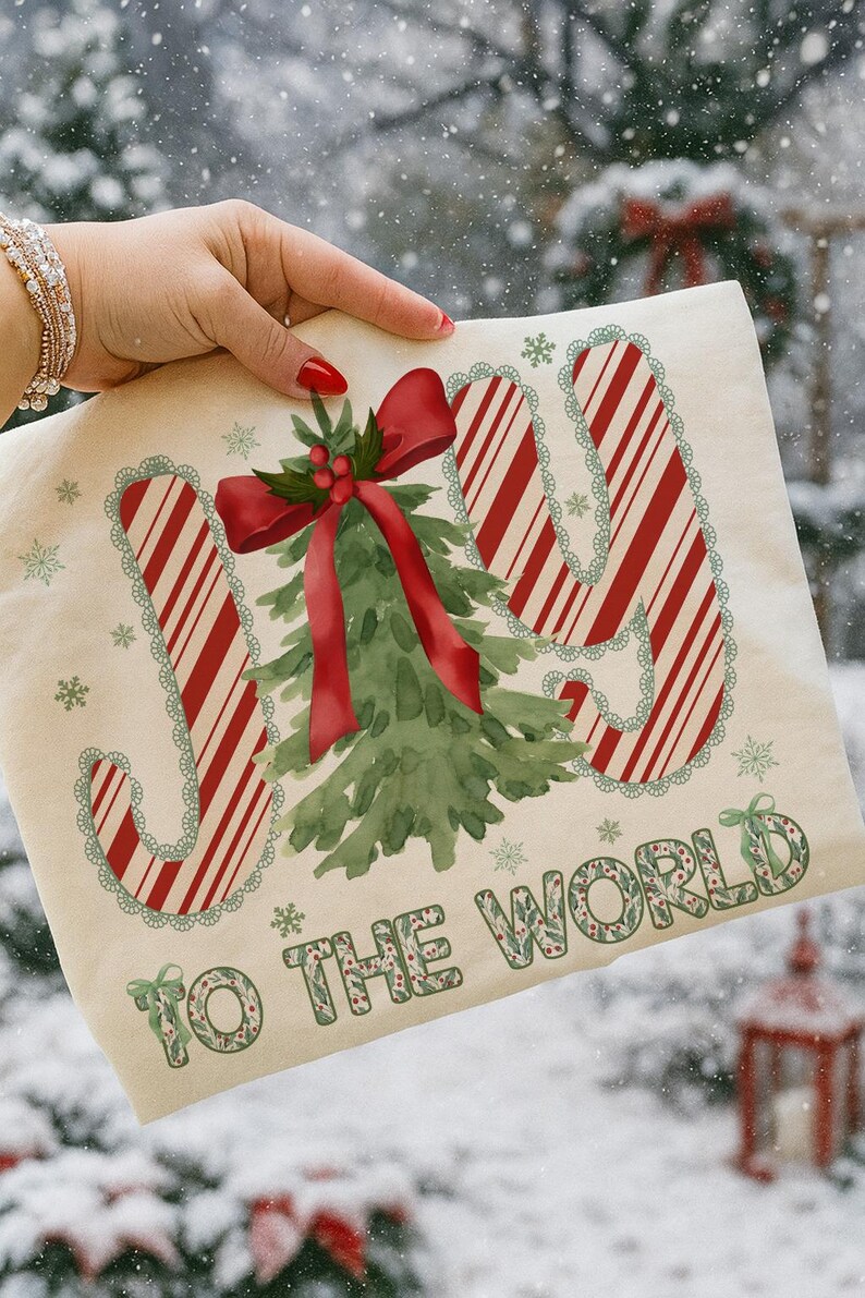 Puede incluir: Un bolso tote navide&ntilde;o color crema con las palabras "JOY TO THE WORLD". La palabra "JOY" est&aacute; en rayas rojas y blancas de bast&oacute;n de caramelo. Un &aacute;rbol de Navidad verde y un lazo rojo est&aacute;n en el centro.