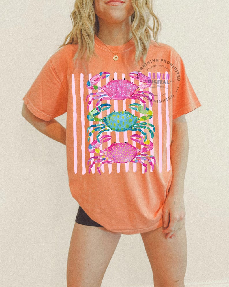 Puede incluir: Camiseta naranja con un patr&oacute;n de rayas blancas verticales y tres ilustraciones de cangrejos coloridos. Los cangrejos son rosas, azules y rosas, con dise&ntilde;os detallados de acuarela. La camiseta tiene el texto "TRAINING PROHIBITED ARWEN DIGITAL COPYRIGHTED".