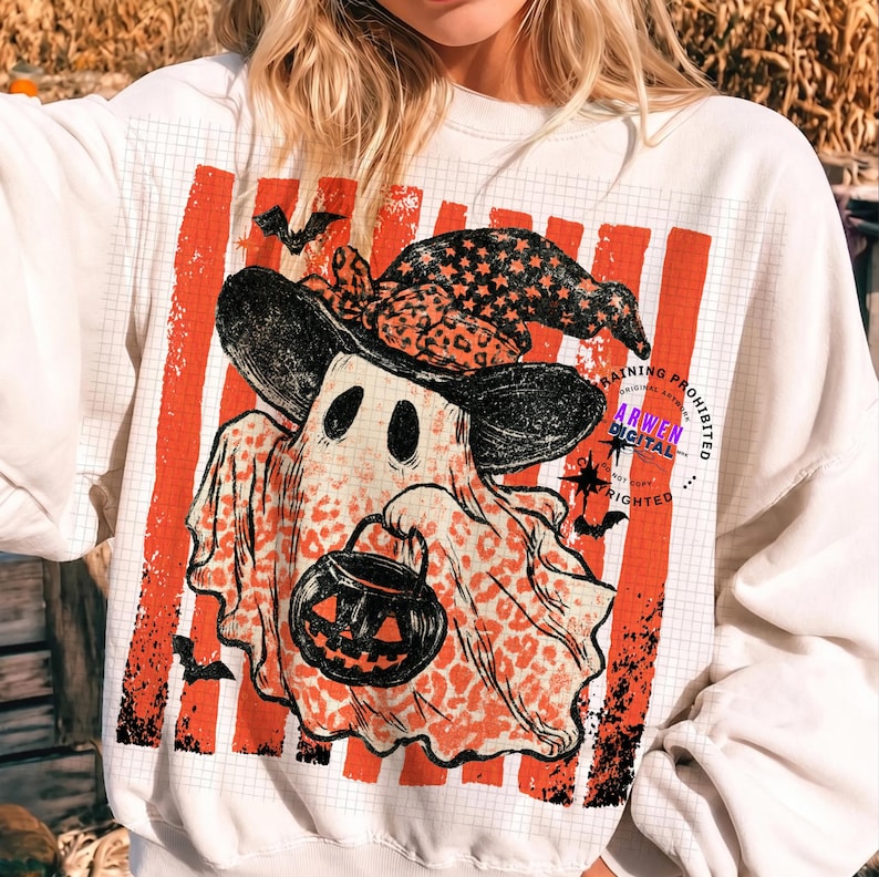 May include: A white crewneck sweatshirt featuring a graphic of a ghost wearing a black star-patterned witch hat and holding a jack-o'-lantern bucket. The ghost has an orange leopard print pattern and is set against a background of vertical orange stripes.