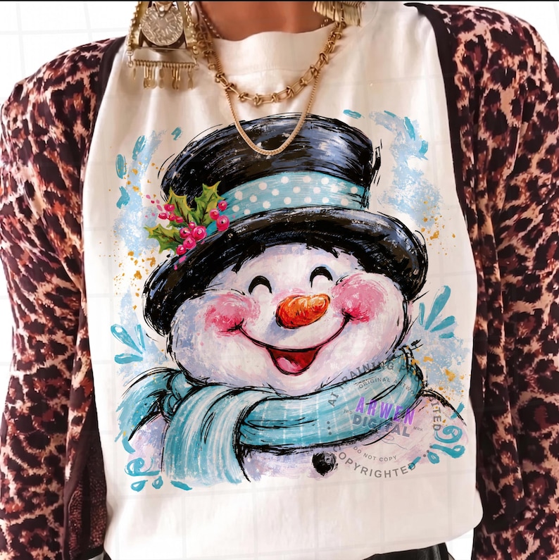 May include: A white t-shirt featuring a graphic illustration of a smiling snowman wearing a black top hat with a light blue polka dot band, a light blue scarf, and a sprig of holly with red berries, layered under a brown and black leopard print cardigan.