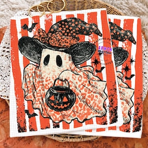 May include: A square print featuring a ghost wearing a black witch hat with a leopard print bow, holding a black jack-o'-lantern bucket. The background has vertical orange and white stripes with black bats and stars. Text reads ARWEN DIGITAL.