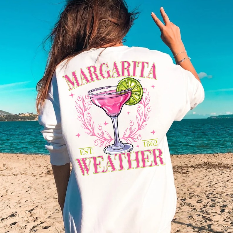 May include: White sweatshirt with a pink margarita graphic and the text "Margarita Weather" with the year "1862" and "Est." printed below.