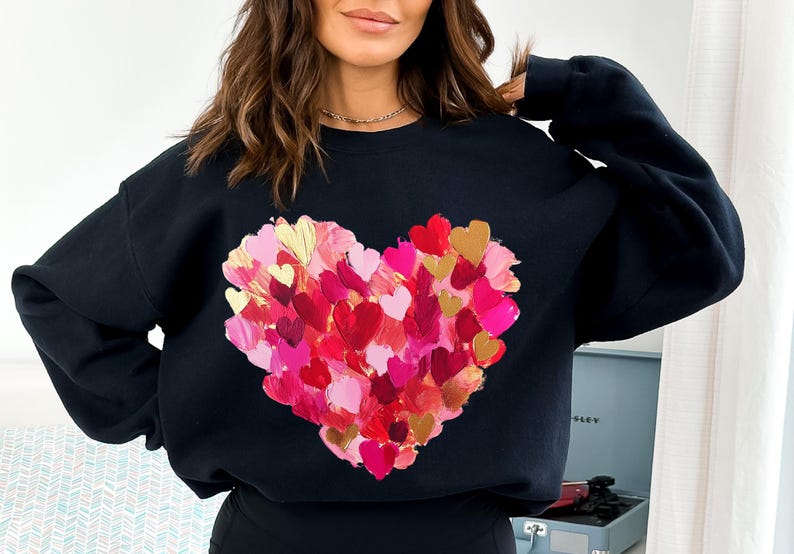 May include: Black sweatshirt with a large heart design made of many smaller painted hearts in shades of pink, red, and gold.