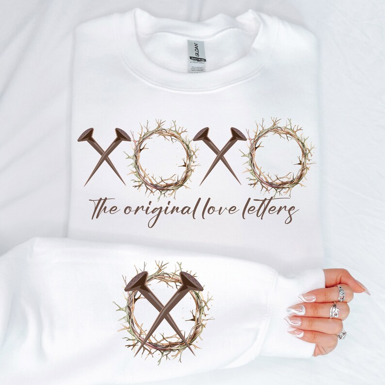May include: White sweatshirt with a brown graphic of a crown of thorns with nails forming the letters "XOXO" and the text "The original love letters".